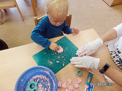 Ein Kind sticht Muster mit Ausstechförmchen aus Teig