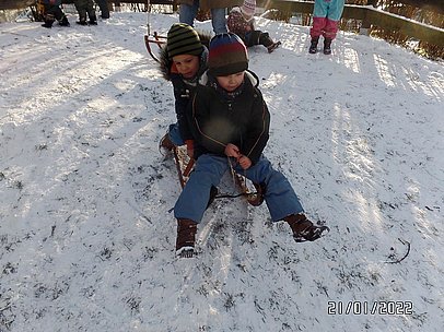 Zwei Kinder rodeln auf einem Schlitten