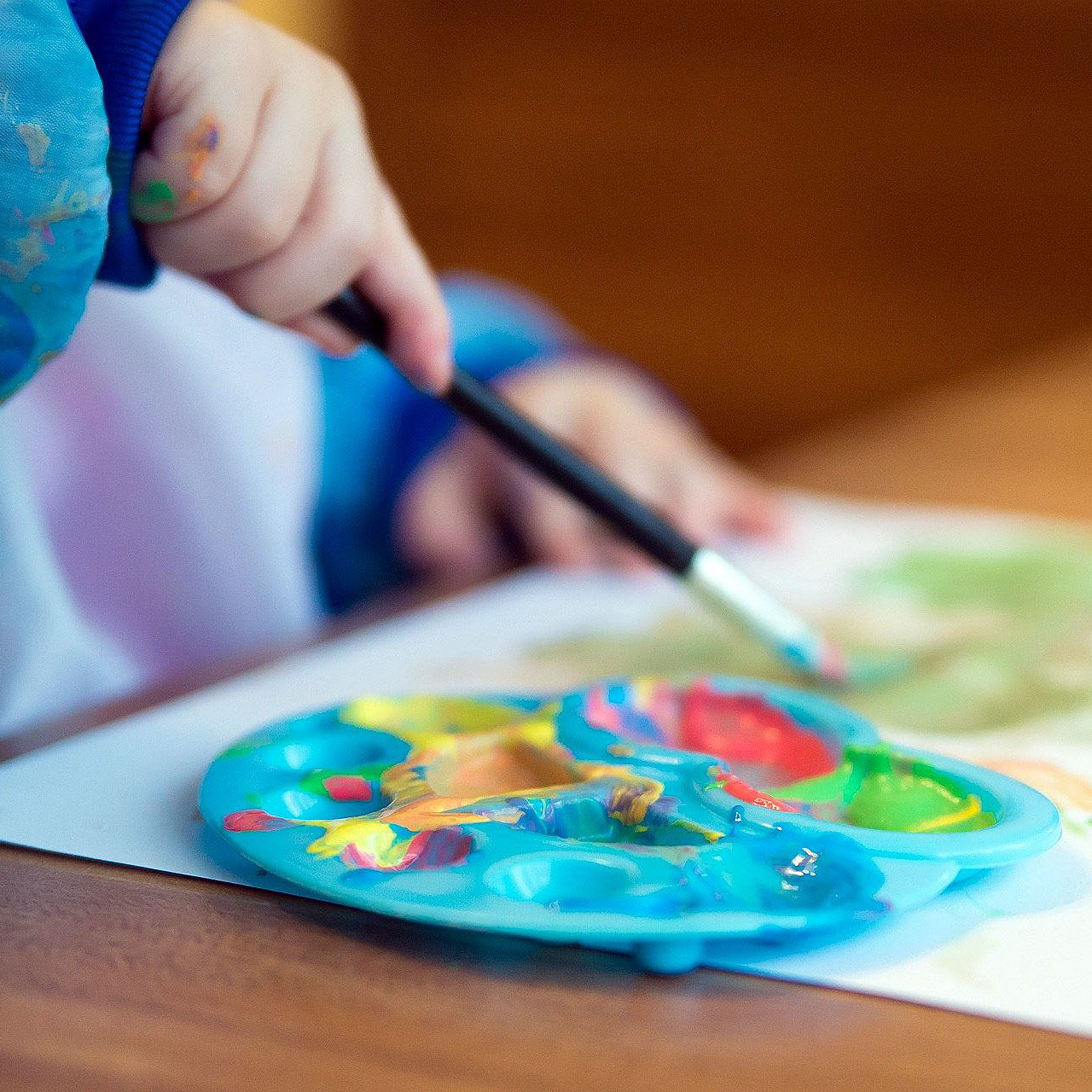 Kind malt mit Pinsel und Farbe ein Bild