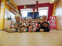 Drei Kinder sitzen auf dem Boden und putzen ihre Schuhe für den Nikolaus