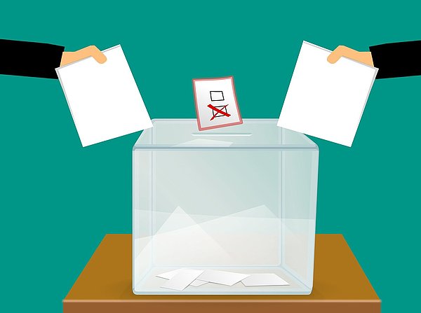 Wahlzettel werden in eine Wahlurne gesteckt Grafik