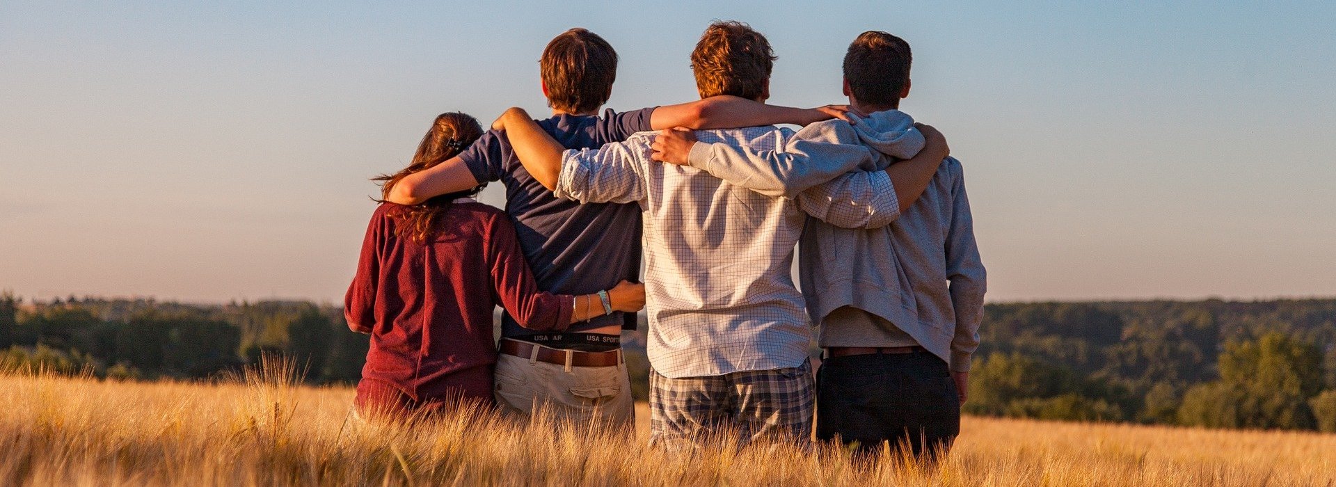 Vier Jugendliche, die sich umfassend auf einem Feld stehen