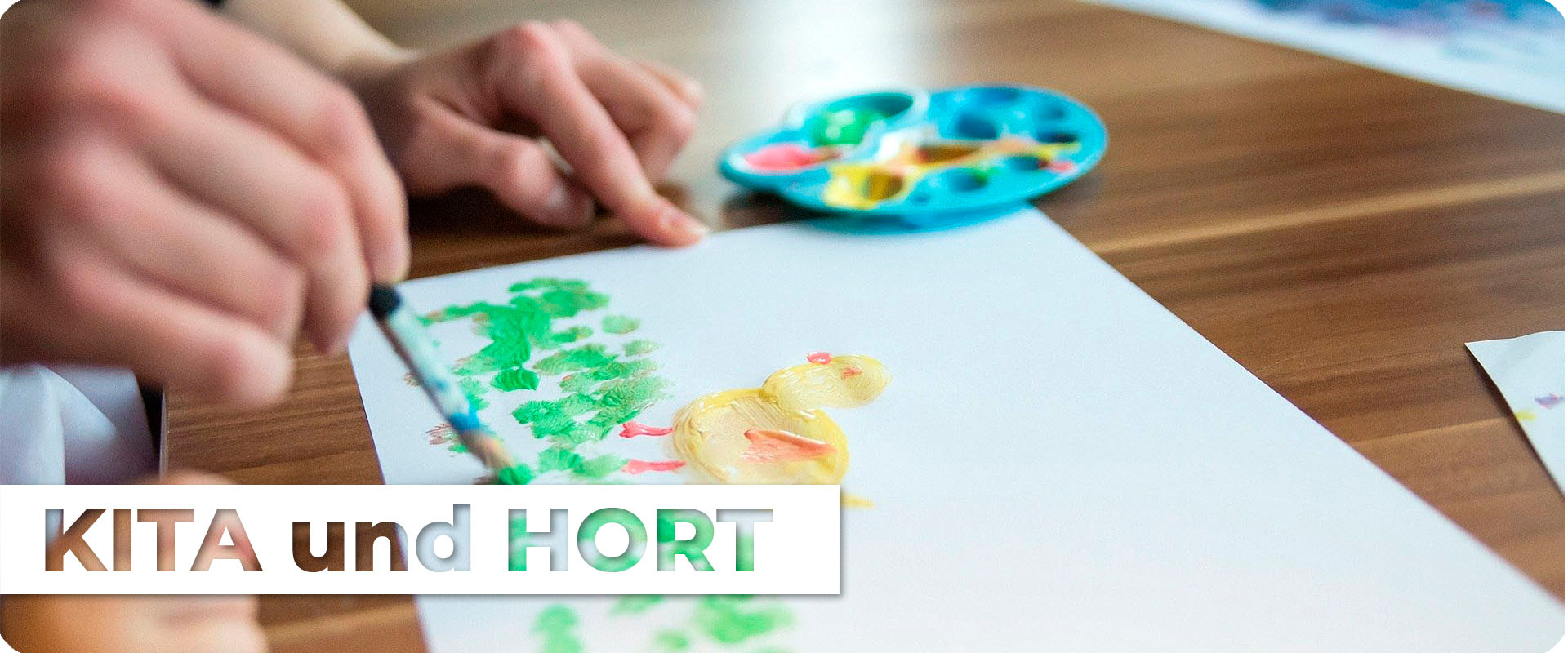 Ein Kleinkind malt mit Hilfe eines Erwacshenen ein Bild mit Pinsel und Deckfarben