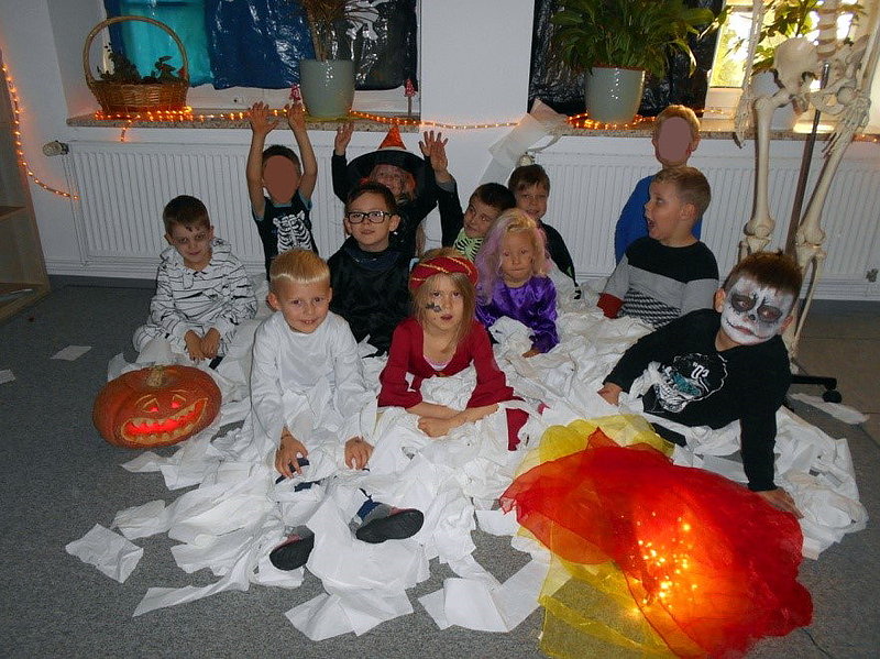 Eine Gruppe Kinder in Halloweenkostümen sitzt in einem Berg ausgewickeltem Toilettenpapier
