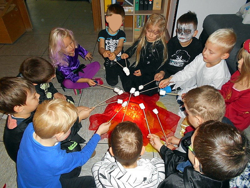 Halloweenkinder grillen Marshmallows über unechtem Feuer